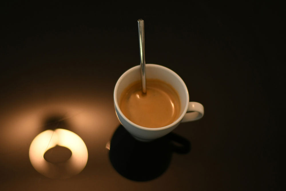 Shot of espresso with a spoon in a dimly lit setting